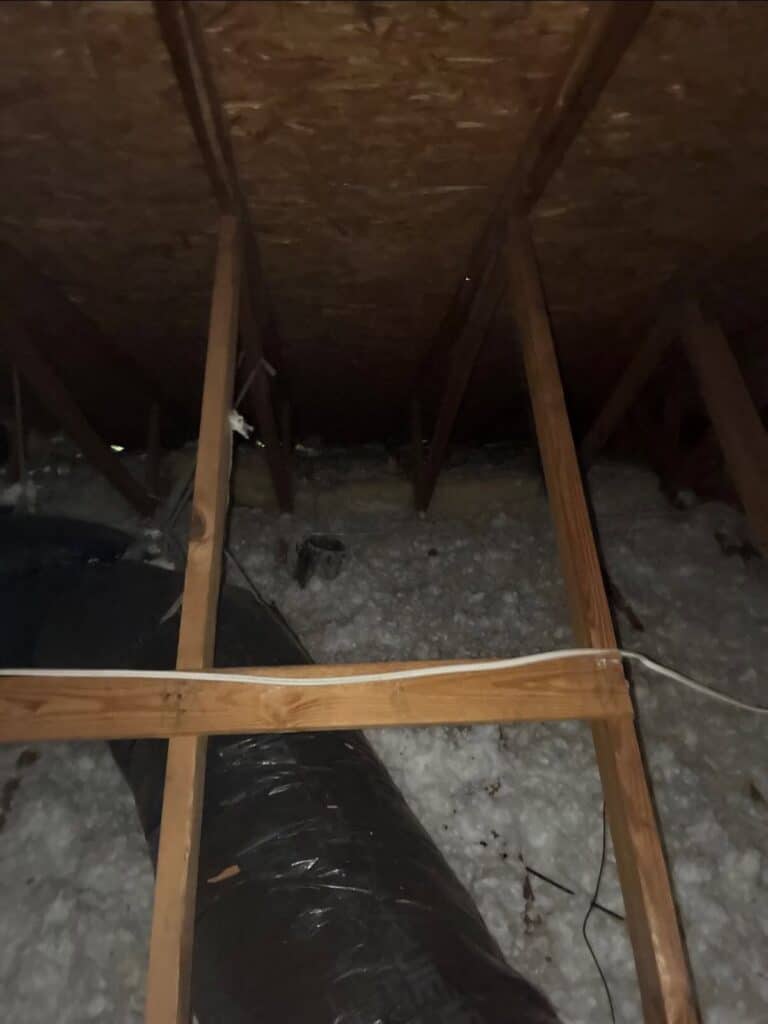 Attic with blown-in insulation on the floor and a bare roof deck