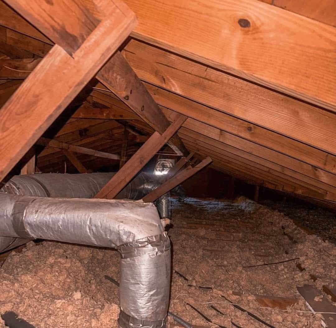 Attic with old loose-fill insulation around AC ductwork