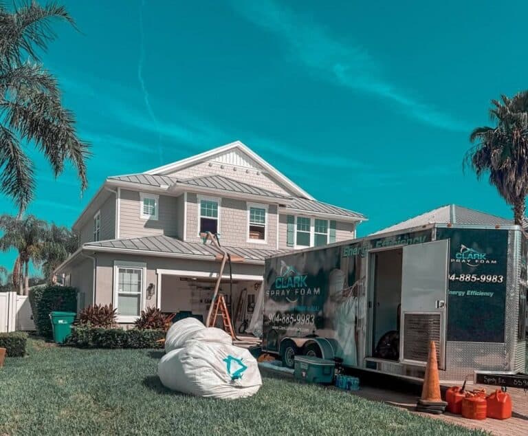 Bags of removed insulation outside a home with the Clark Spray Foam trailer