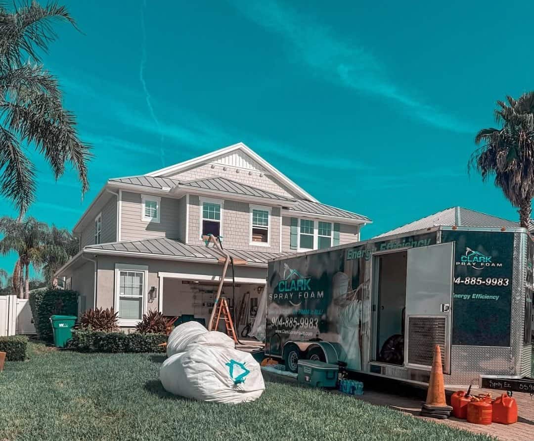 Bags of removed insulation outside a home with the Clark Spray Foam trailer