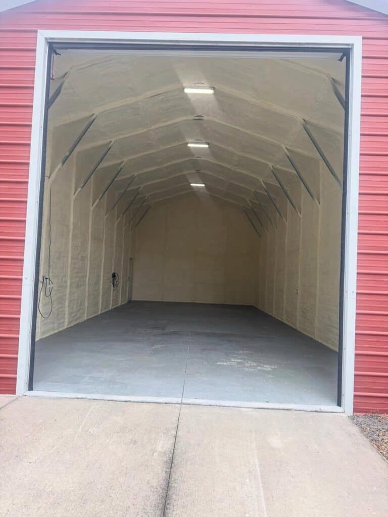 Metal garage building with spray foam insulation, seen through the open bay door