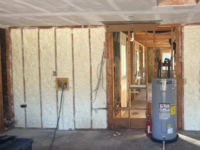 Spray foam insulation between wall studs during a home remodel